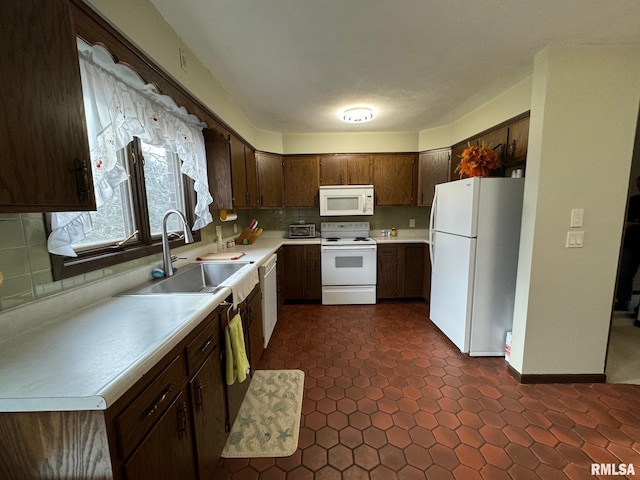 kitchen with dark brown cabinetry, white appliances, sink, and tasteful backsplash