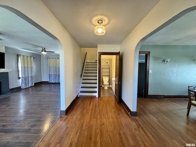 foyer entrance featuring a fireplace, ceiling fan, and dark wood-type flooring