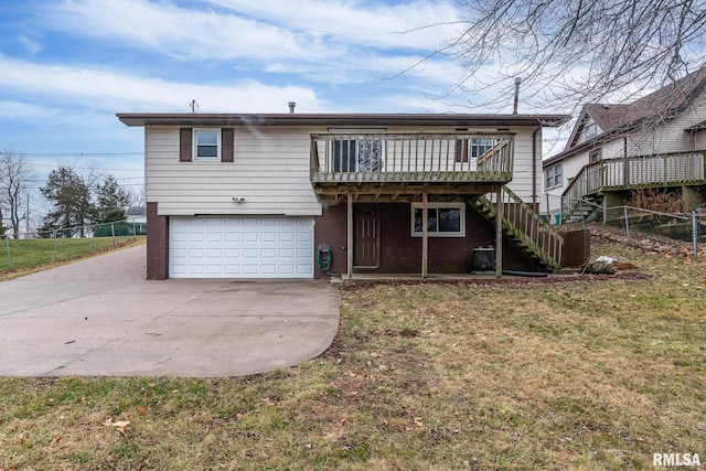 rear view of property with a garage, a lawn, and a wooden deck