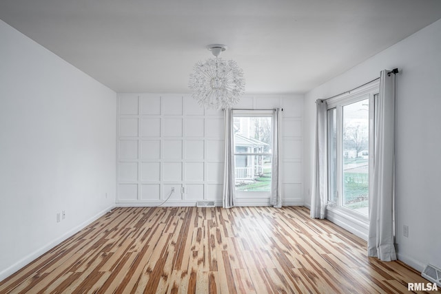 empty room featuring hardwood / wood-style flooring and an inviting chandelier