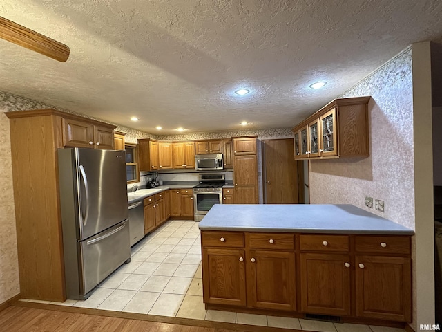 kitchen with appliances with stainless steel finishes, a textured ceiling, light tile patterned floors, and sink