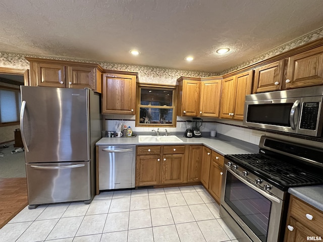 kitchen featuring light tile patterned floors, a textured ceiling, stainless steel appliances, and sink