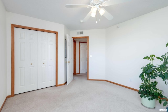 unfurnished bedroom featuring a closet, light colored carpet, and ceiling fan