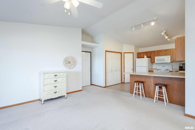 kitchen featuring a kitchen breakfast bar, kitchen peninsula, light colored carpet, lofted ceiling, and white appliances