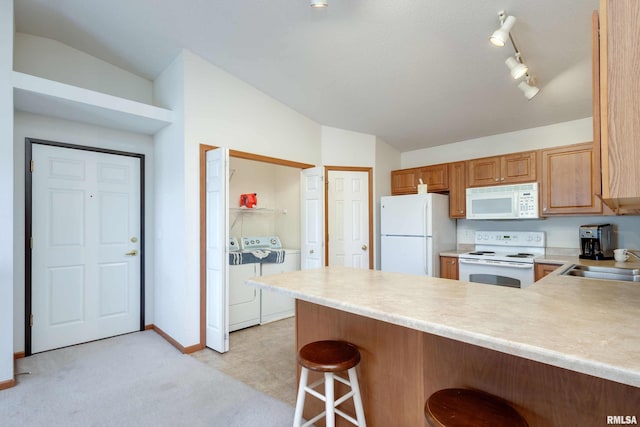 kitchen featuring washer and clothes dryer, lofted ceiling, white appliances, sink, and kitchen peninsula