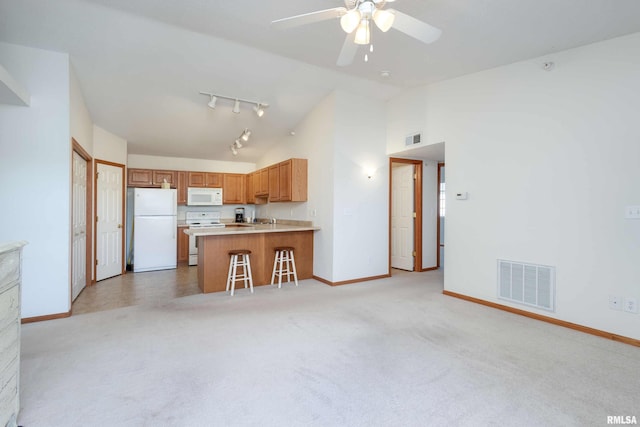 kitchen featuring vaulted ceiling, kitchen peninsula, light carpet, and white appliances