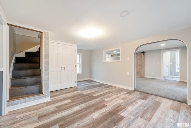 unfurnished room with a barn door and light hardwood / wood-style floors