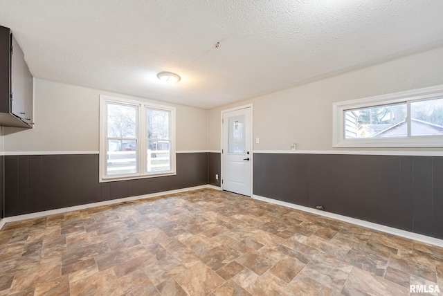 unfurnished room with a textured ceiling and wood walls