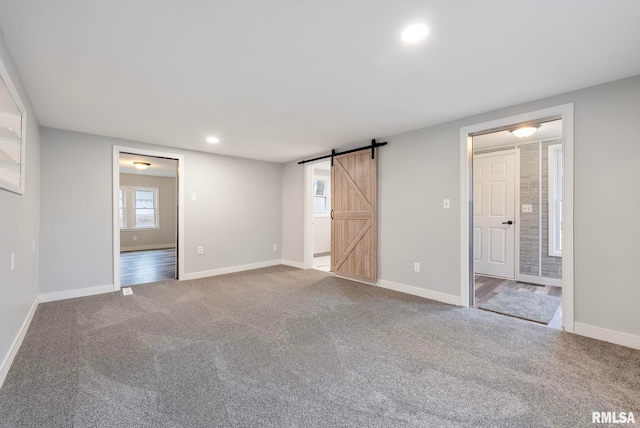 carpeted empty room with a barn door