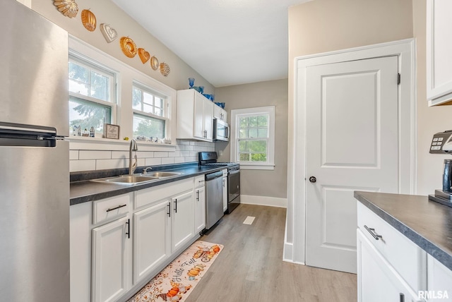 kitchen with sink, light wood-type flooring, appliances with stainless steel finishes, tasteful backsplash, and white cabinetry