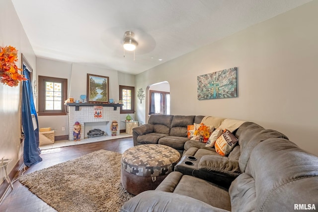 living room with ceiling fan, a healthy amount of sunlight, wood-type flooring, and a fireplace