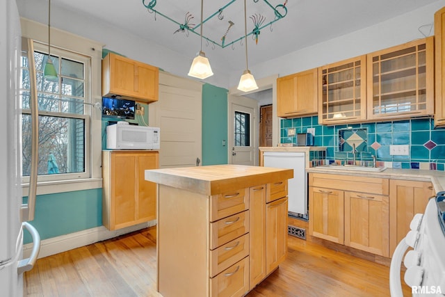 kitchen featuring light brown cabinets, pendant lighting, white appliances, decorative backsplash, and a kitchen island