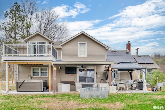 back of house with ceiling fan, a hot tub, a balcony, a gazebo, and a patio