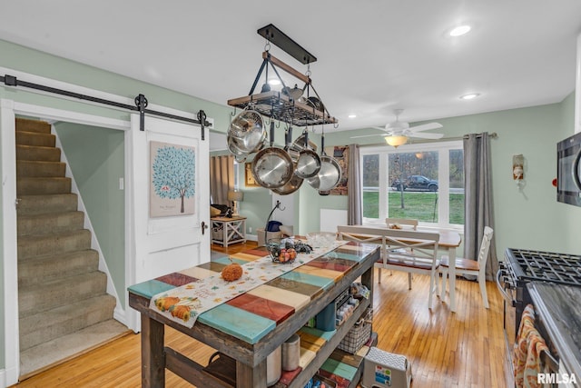 dining area featuring a barn door, ceiling fan, and hardwood / wood-style floors