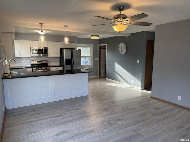 kitchen featuring white cabinetry, ceiling fan, sink, stainless steel appliances, and pendant lighting