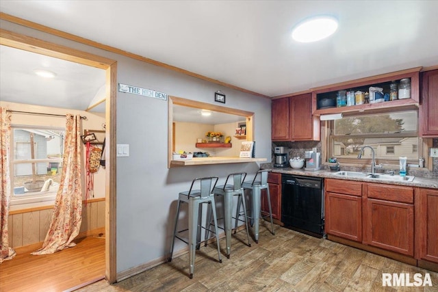 kitchen with hardwood / wood-style floors, plenty of natural light, sink, and black dishwasher