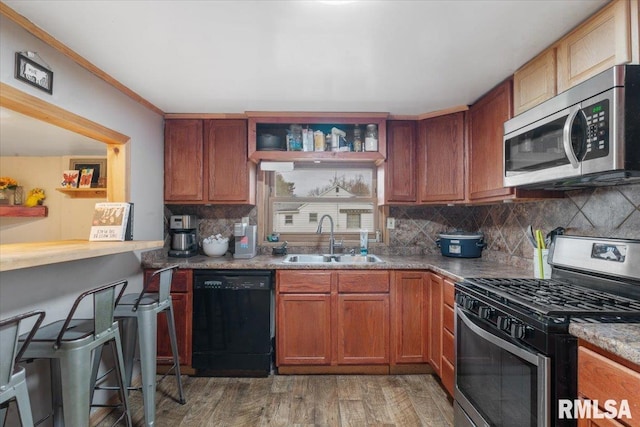 kitchen with sink, light stone counters, hardwood / wood-style floors, decorative backsplash, and appliances with stainless steel finishes