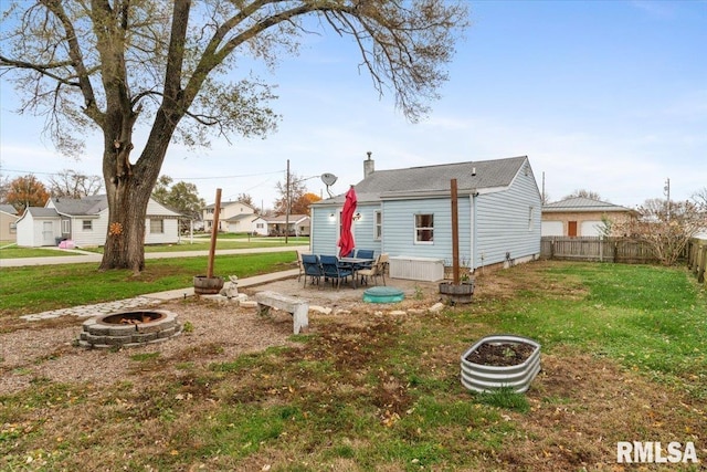 rear view of property with a yard and an outdoor fire pit