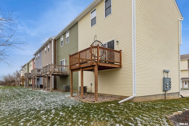 snow covered property featuring central air condition unit, a yard, and a deck