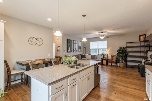 kitchen featuring dishwasher, sink, pendant lighting, a kitchen island with sink, and white cabinets