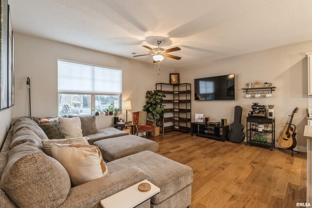 living room with a textured ceiling, light hardwood / wood-style flooring, and ceiling fan