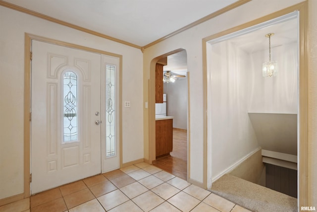 foyer entrance with light tile patterned floors, ceiling fan with notable chandelier, and ornamental molding