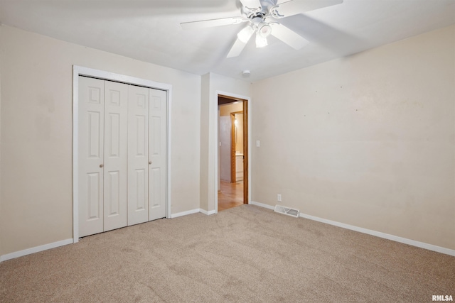 unfurnished bedroom featuring ceiling fan, a closet, and light carpet