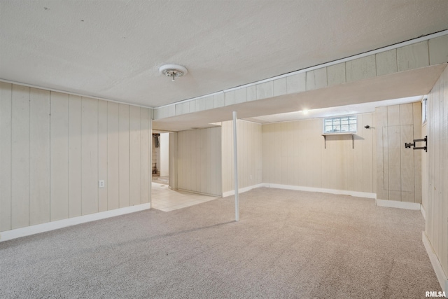 basement featuring light carpet, a textured ceiling, and wood walls