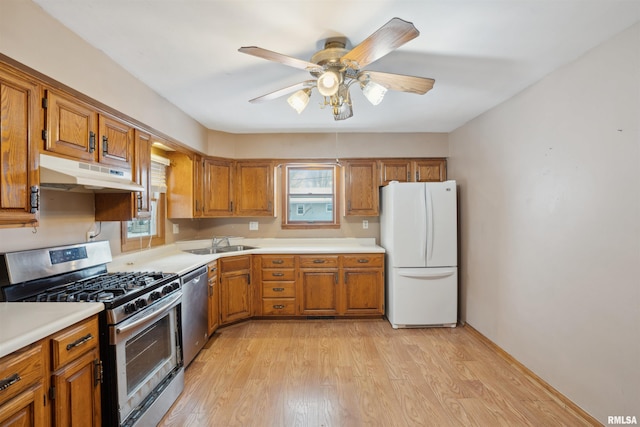 kitchen with ceiling fan, sink, stainless steel appliances, and light hardwood / wood-style floors