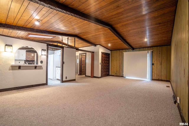 carpeted spare room with lofted ceiling with beams, wooden ceiling, and wood walls