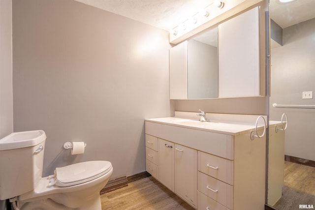 bathroom with vanity, toilet, wood-type flooring, and a textured ceiling