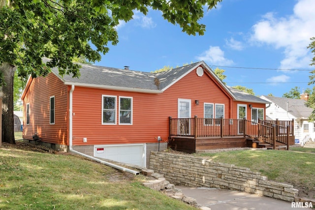 back of property featuring a garage, a deck, and a lawn