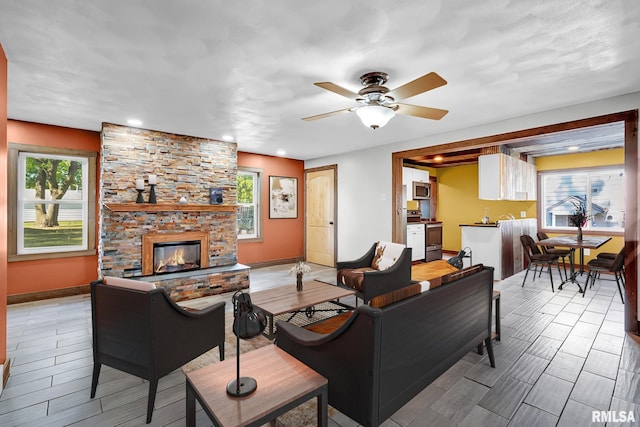 living room with ceiling fan and a fireplace