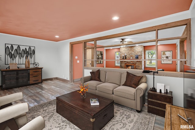 living room featuring crown molding, ceiling fan, a fireplace, and wood-type flooring