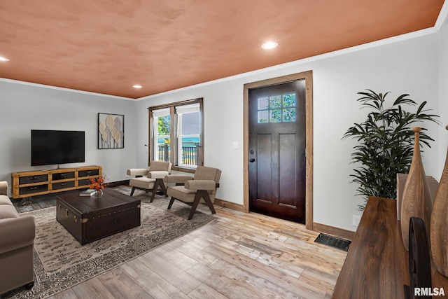 living room with light wood-type flooring and ornamental molding