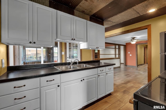 kitchen featuring ceiling fan, sink, range, white cabinetry, and plenty of natural light