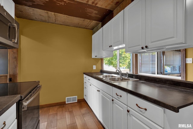 kitchen featuring white cabinets, light hardwood / wood-style flooring, wood ceiling, and sink