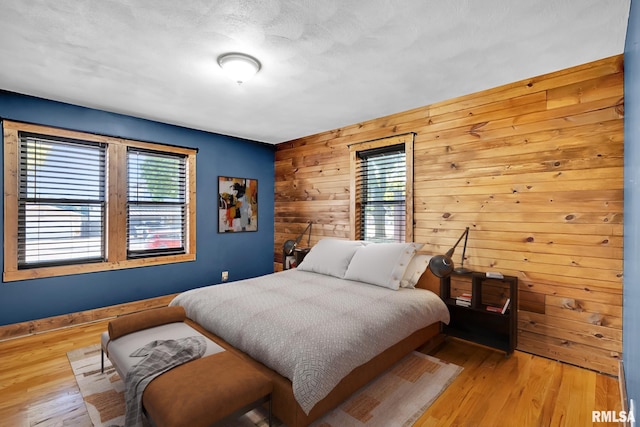 bedroom featuring light hardwood / wood-style flooring and wood walls