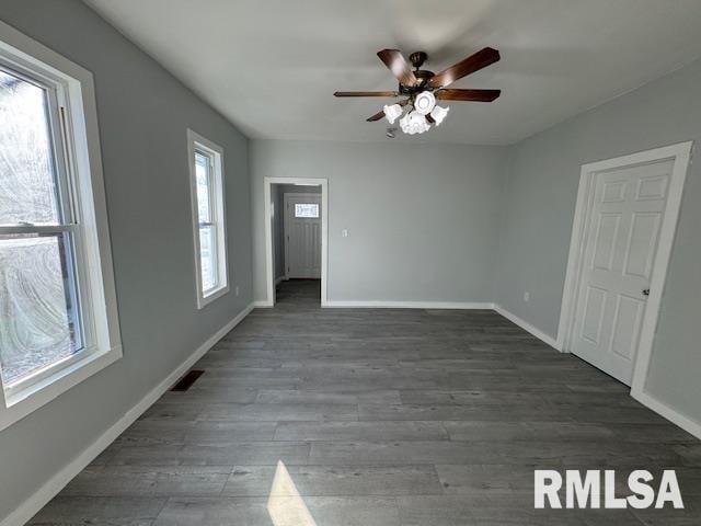 unfurnished room featuring ceiling fan, plenty of natural light, and dark wood-type flooring