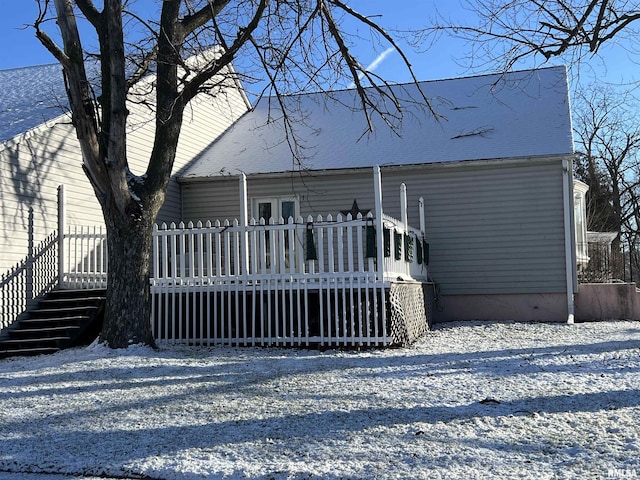 snow covered house featuring a wooden deck