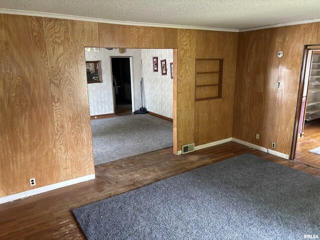 560 4th Ave S, Clinton, IA 52732 - spare room with a textured ceiling, ornamental molding, wooden walls, baseboards, and wood finished floors
