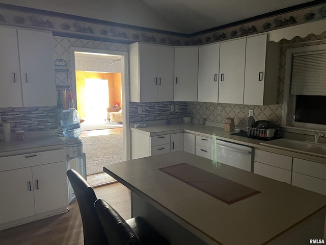 kitchen with lofted ceiling, white dishwasher, and white cabinets