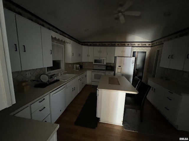 kitchen with vaulted ceiling, a kitchen island, sink, white cabinets, and white appliances