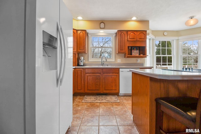 kitchen with light tile patterned flooring, white appliances, and sink