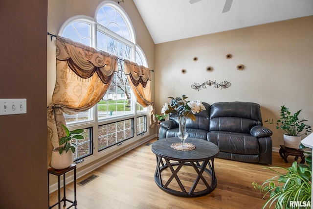 living room with ceiling fan, a healthy amount of sunlight, vaulted ceiling, and light hardwood / wood-style flooring