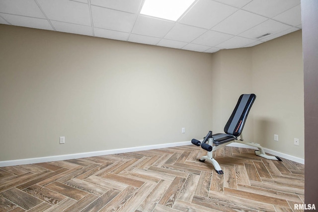 workout room with a drop ceiling and parquet flooring