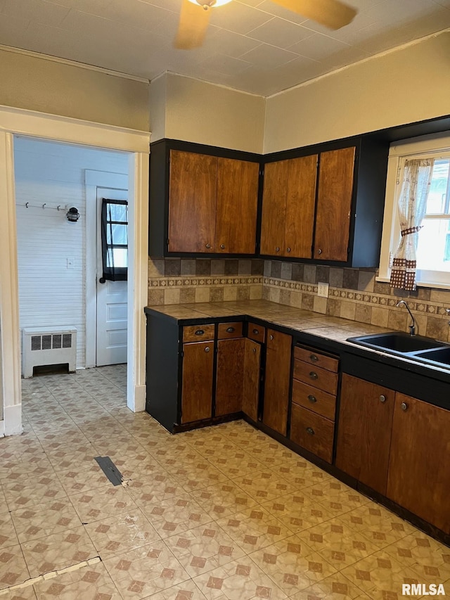 kitchen featuring decorative backsplash, ceiling fan, sink, and radiator