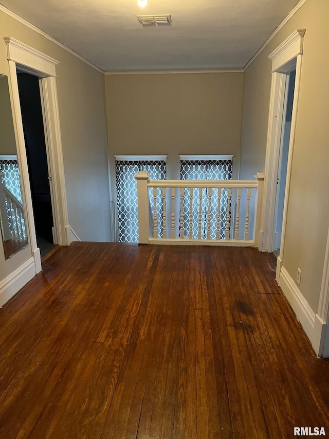 empty room featuring dark wood-type flooring and ornamental molding