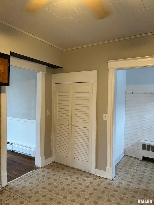 corridor featuring a barn door, ornamental molding, a baseboard radiator, and radiator