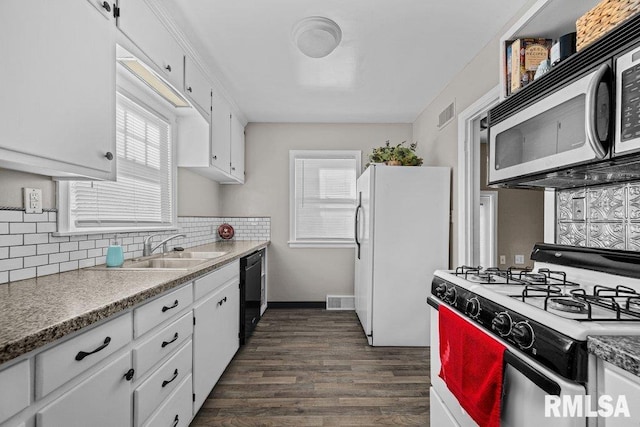 kitchen featuring white appliances, white cabinetry, a barn door, and backsplash